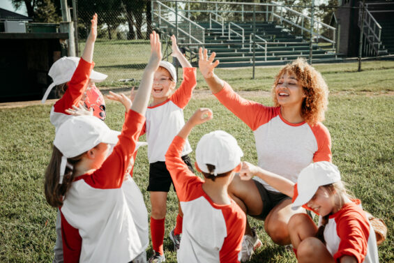 A little league team celebrates with their coach.