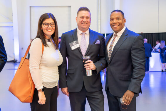 Three business people smile at the camera at an event put on by Kansas Commerce.