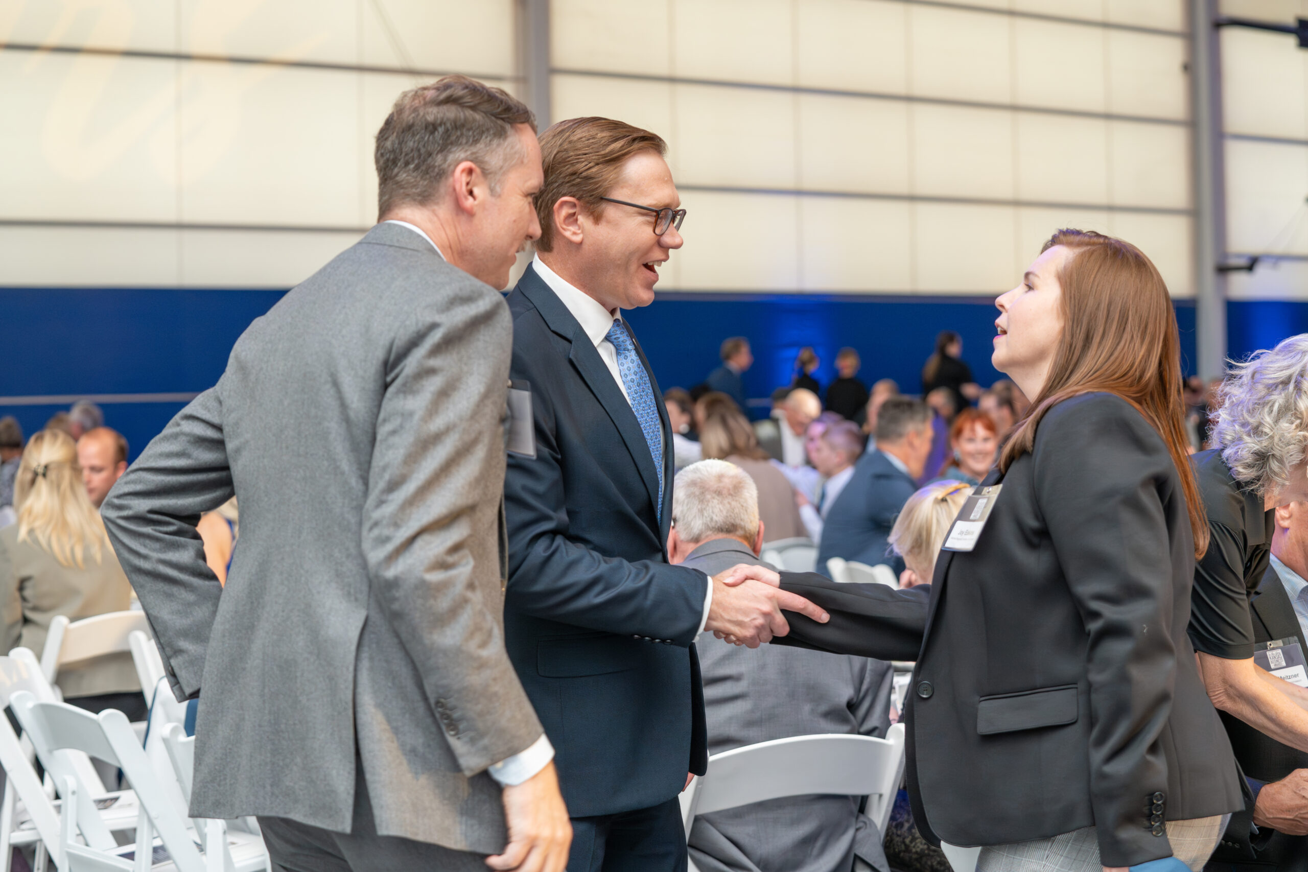 A businessman and businesswoman shake hands at an event.