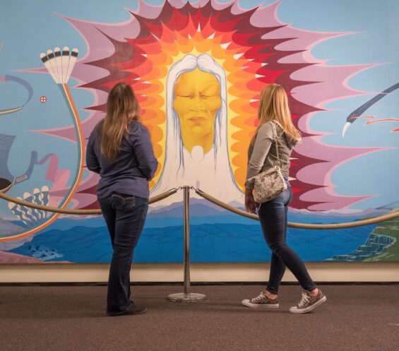 Two women enjoy a large, beautiful painting at the Mid-America Indian Center.