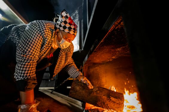 BBQ chef puts more hickory wood into a wood-burning oven