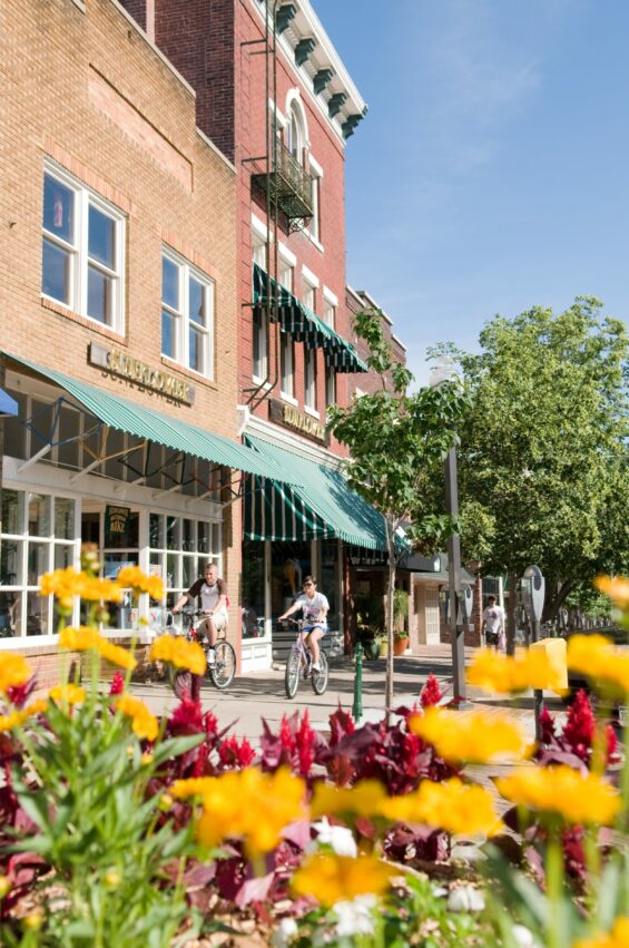 Two people bike on the sunny sidewalk in Lawrence, Kansas