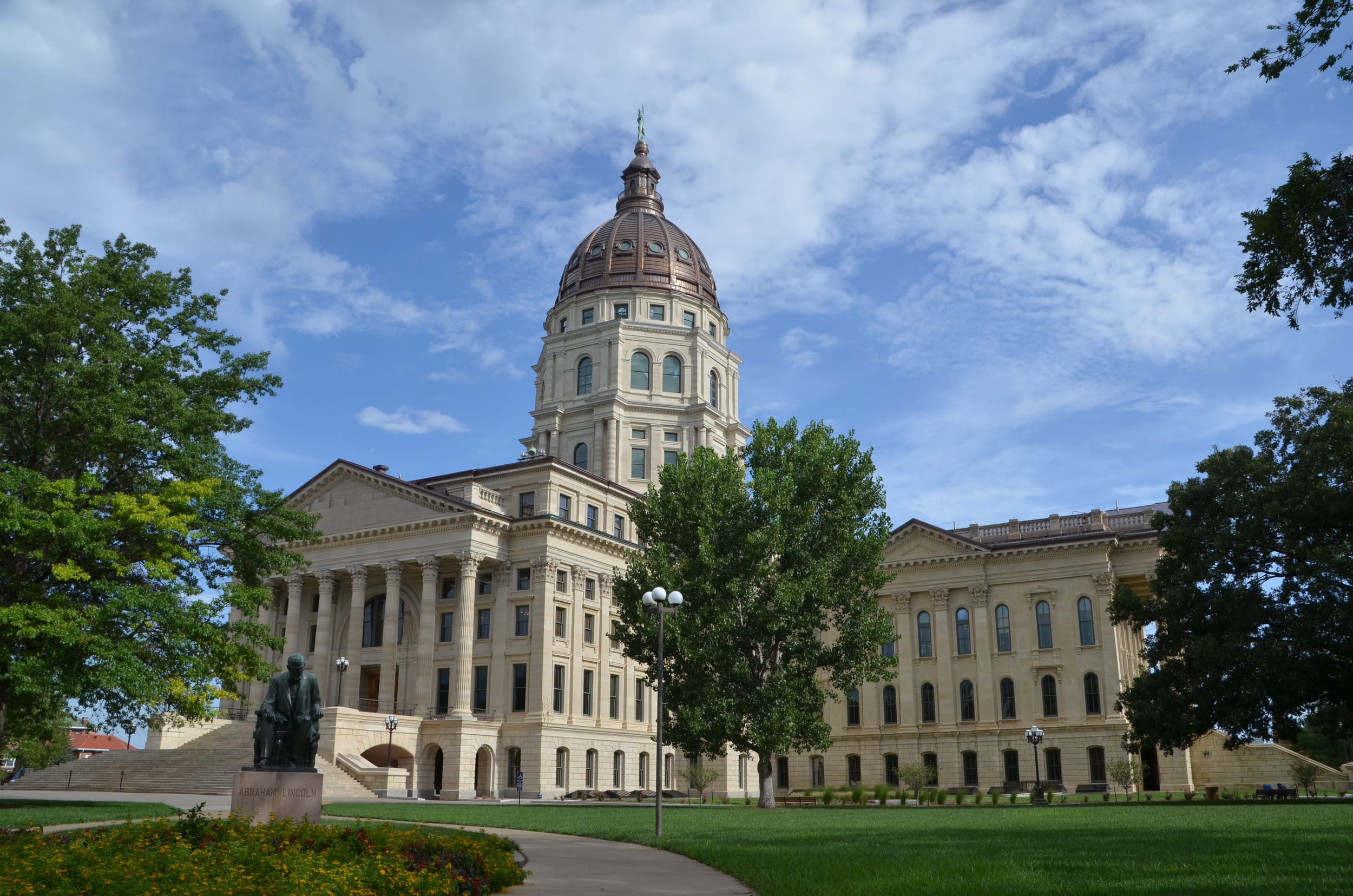 Kansas capital building, a large white bricked building with a tall central dome, on a sunny day.