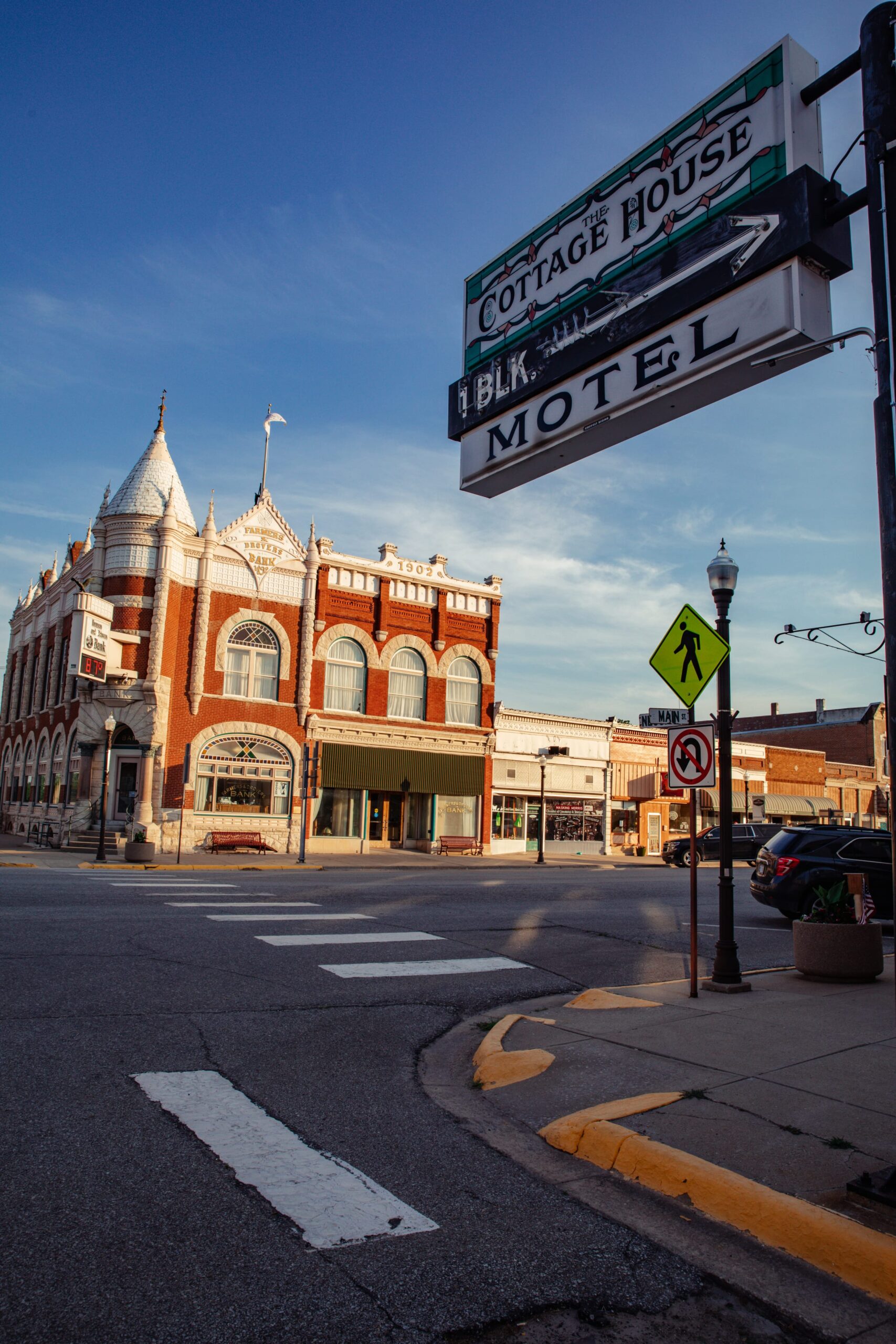 Close-up of the Cottage House Motel sign across the street from the historic, red-bricked Farmer's Drove bank.