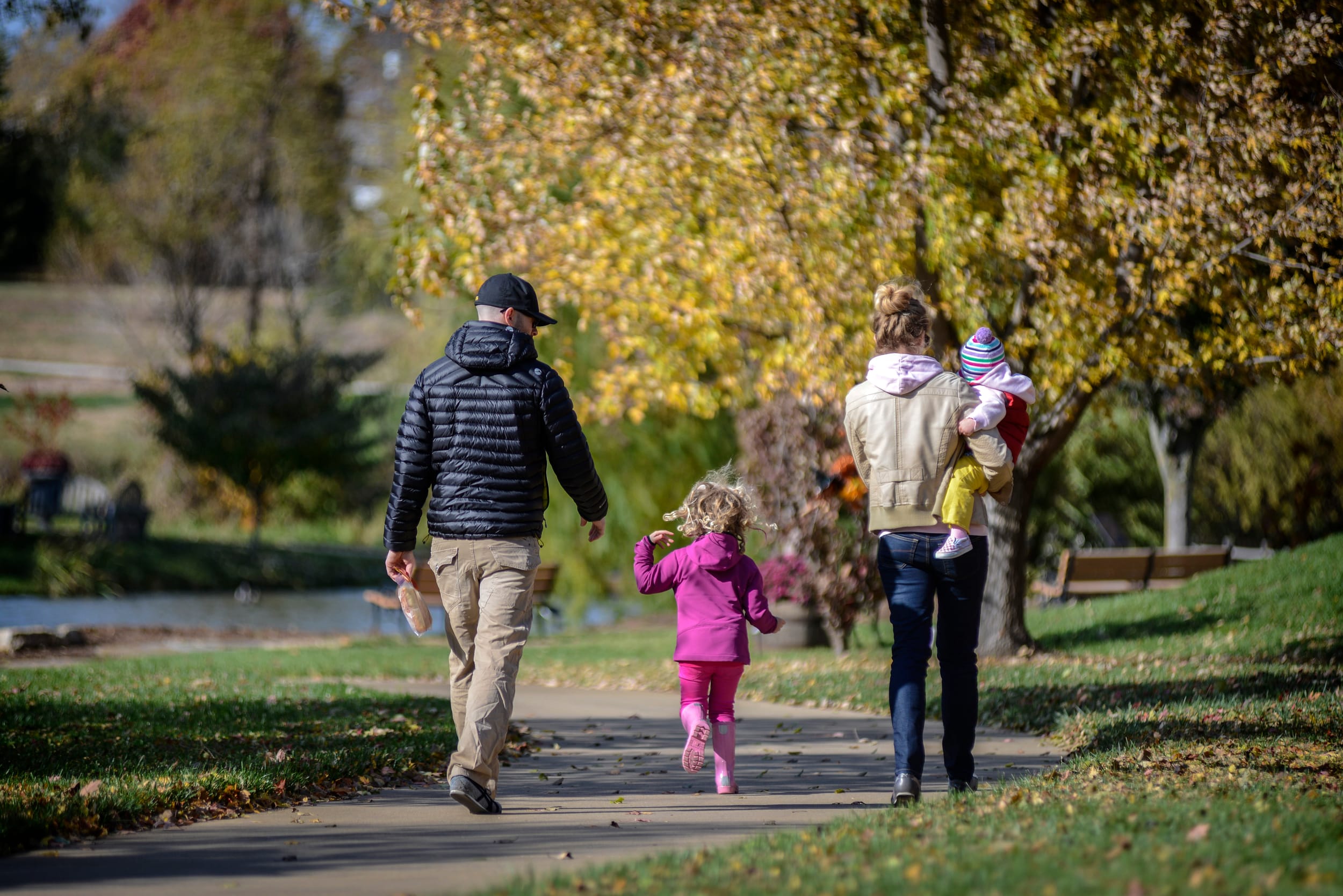 Parents and two small children walk in the Overland Park Arboretum and Botanical Garden